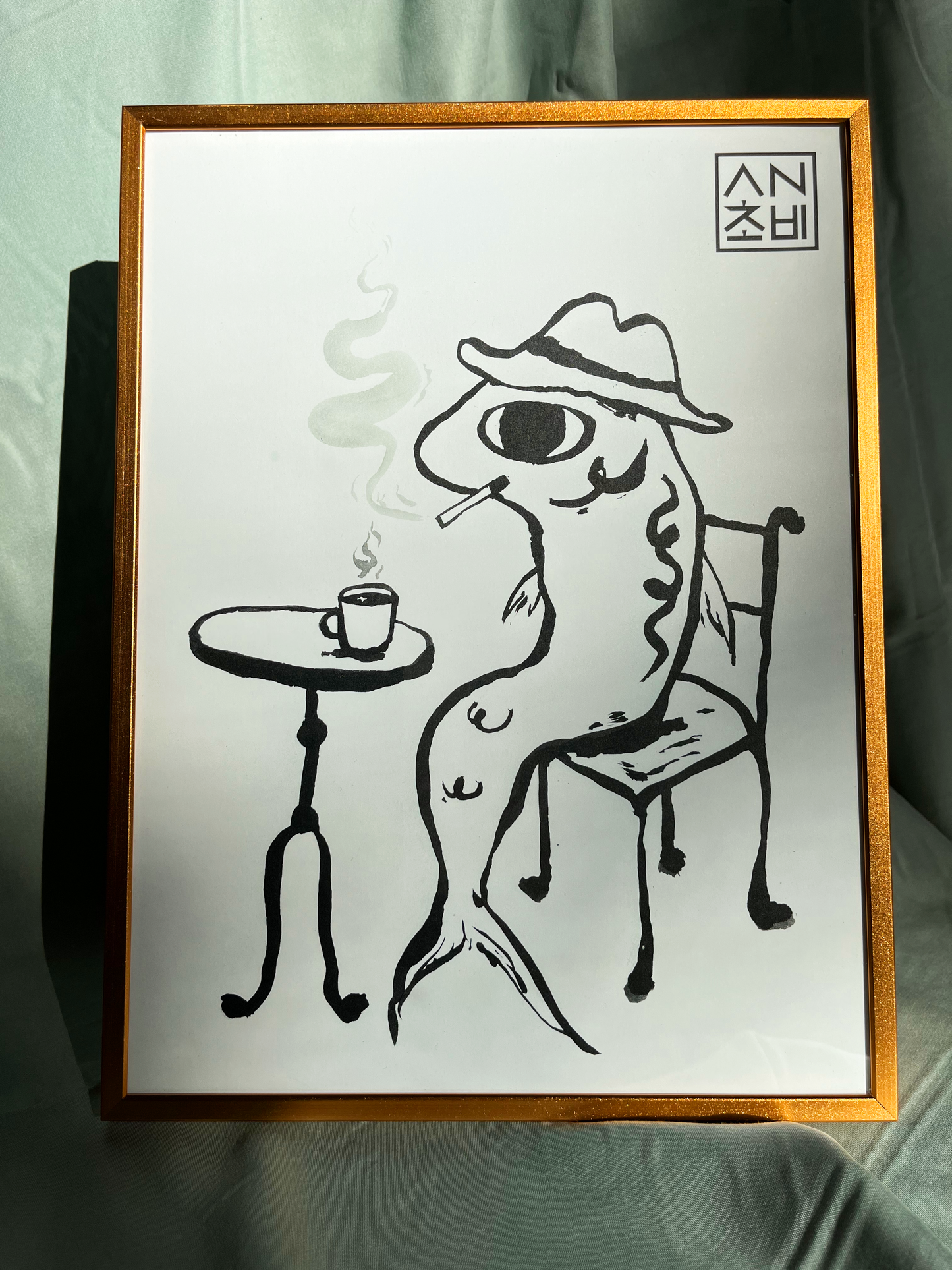 9x12 Matte Finish Black and White Art Print for home, apartment, and room decor. Featured here in a gold frame. Anchovy Studio design original print by independent artists. Inspired by calligraphy and expressionism. In this artwork, an anchovy smokes a cigarette with a cup of coffee, head full of thoughts.