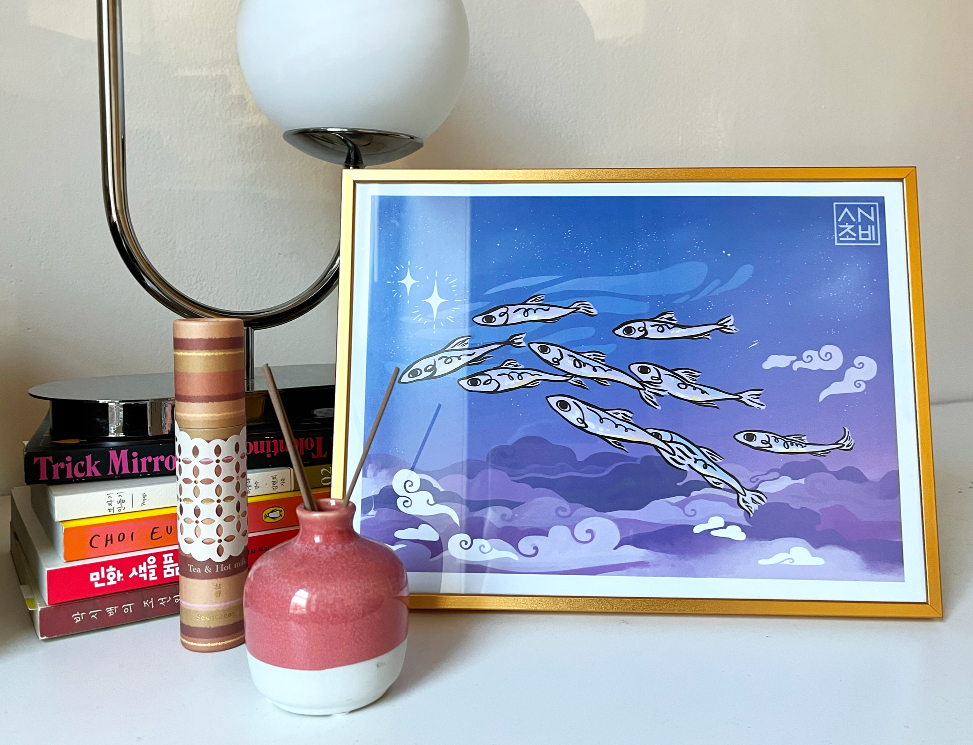 9x12 Gloss Finish Color Art Print in full color for home, apartment, or room decor. A school of anchovies flies together in the evening sky among blue and purple clouds and stars. Anchovy Studio original design by independent artists. Featured here in a gold frame.